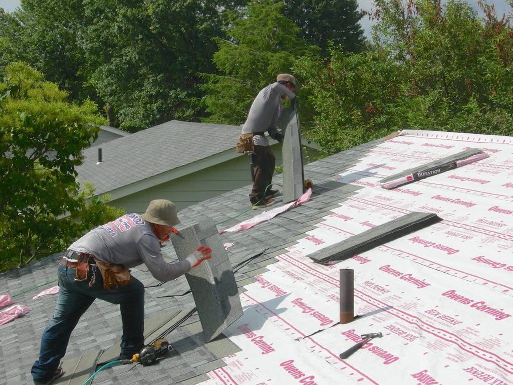 Two men working on a roof with some tape
