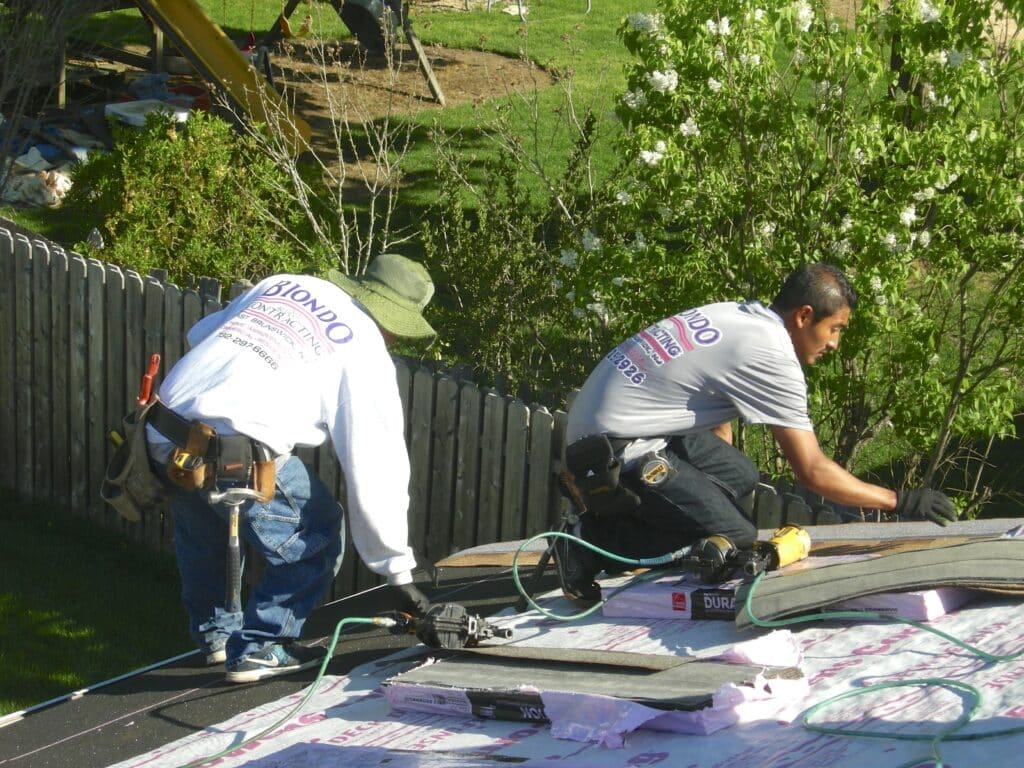 Roofers nailing roofing shingles