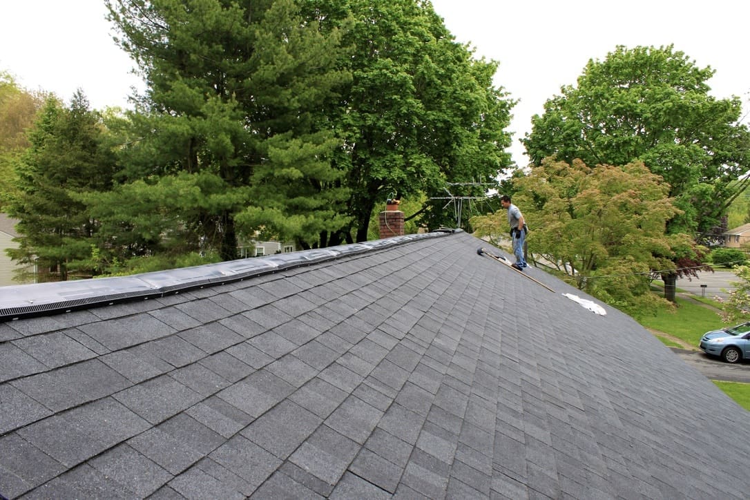 A person installing ridge vents on top of a roof.