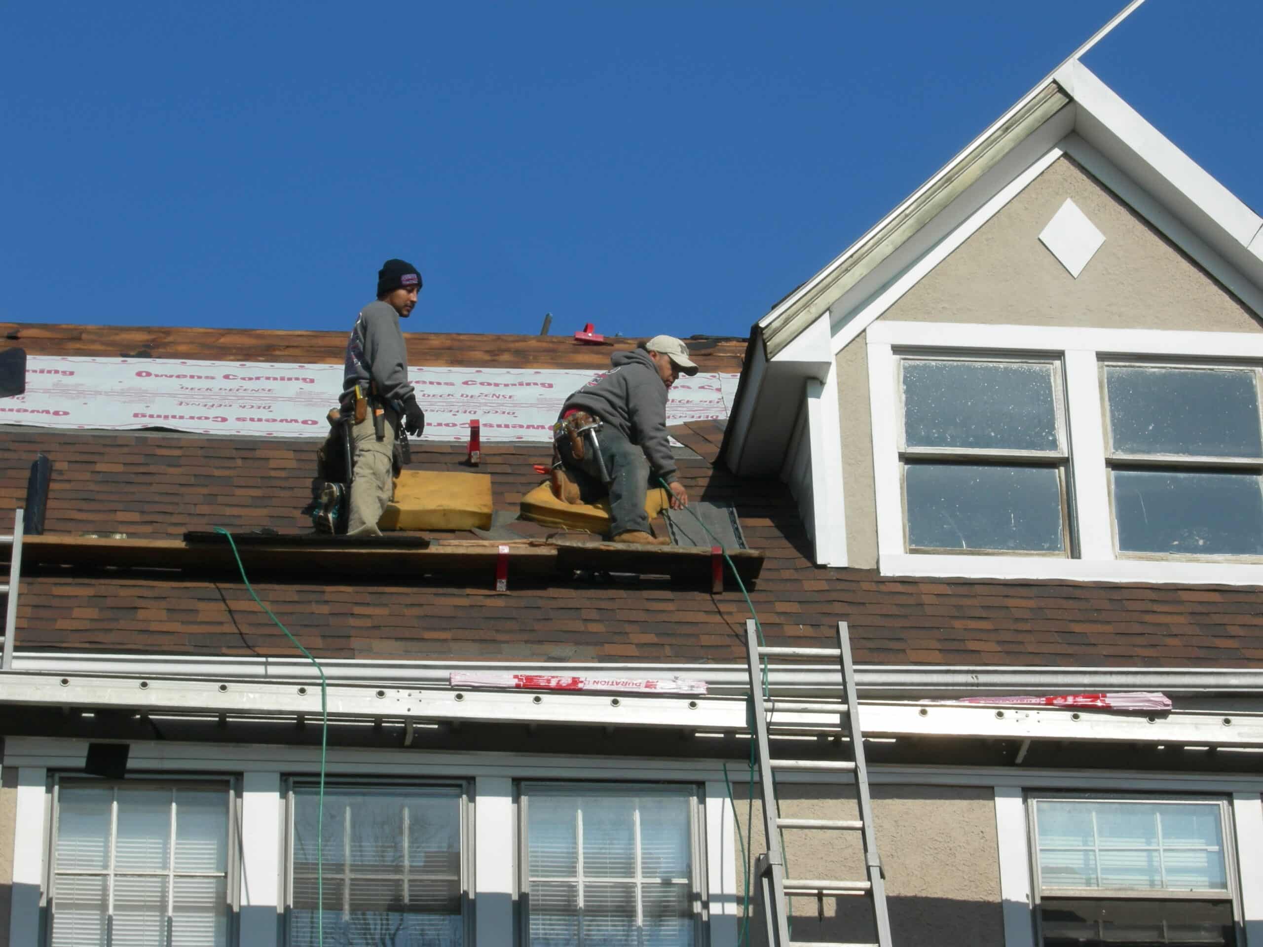 Two men working on a roof of a house.