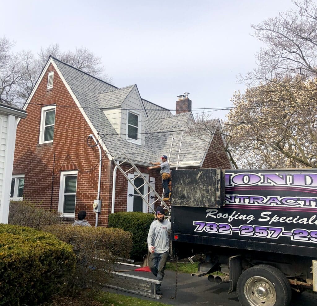 A man standing next to a truck in front of a house. East Brunswick Roof Repair