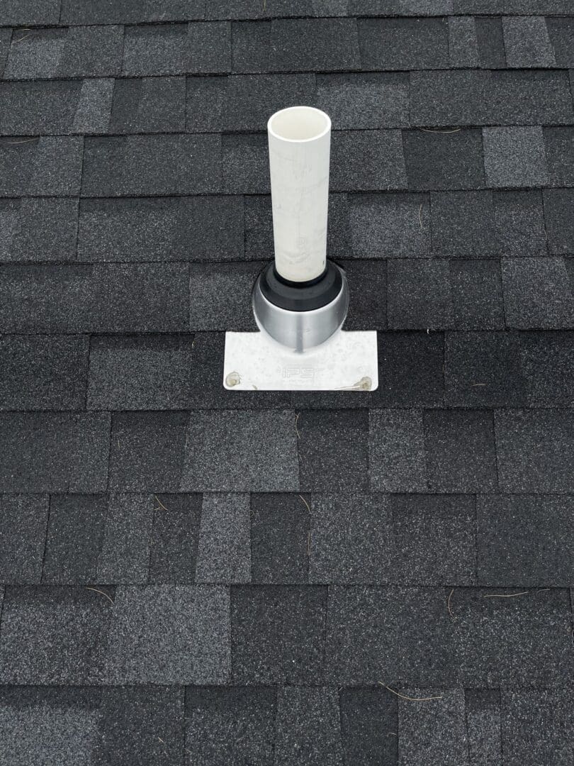 A black roof with a white pipe going through top of it.