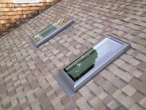 A pair of skylights on the side of a brick building.