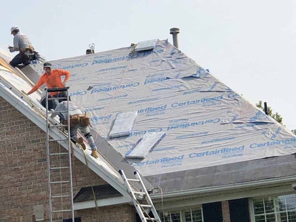 A man standing on the roof of a house. Installing a high performance synthetic underlayment-new jersey residential roofing