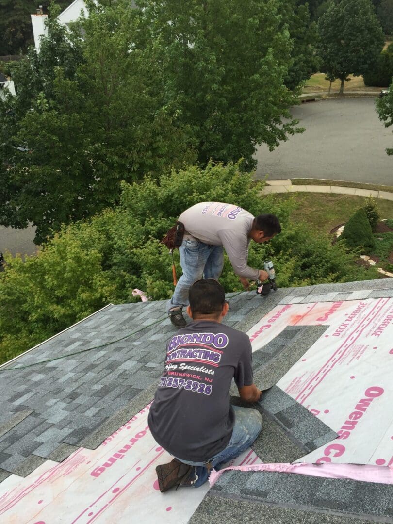 2 men installing roof shingles on a house