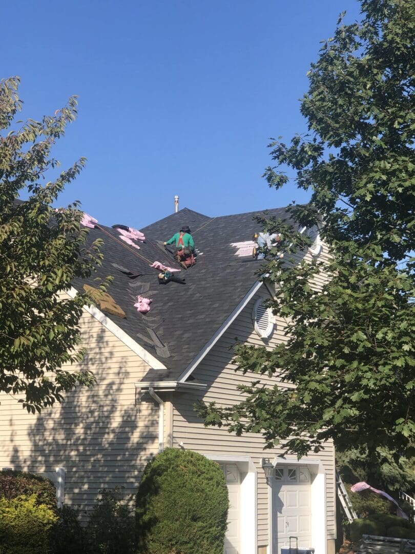 a man installing roof shingles on top of a house