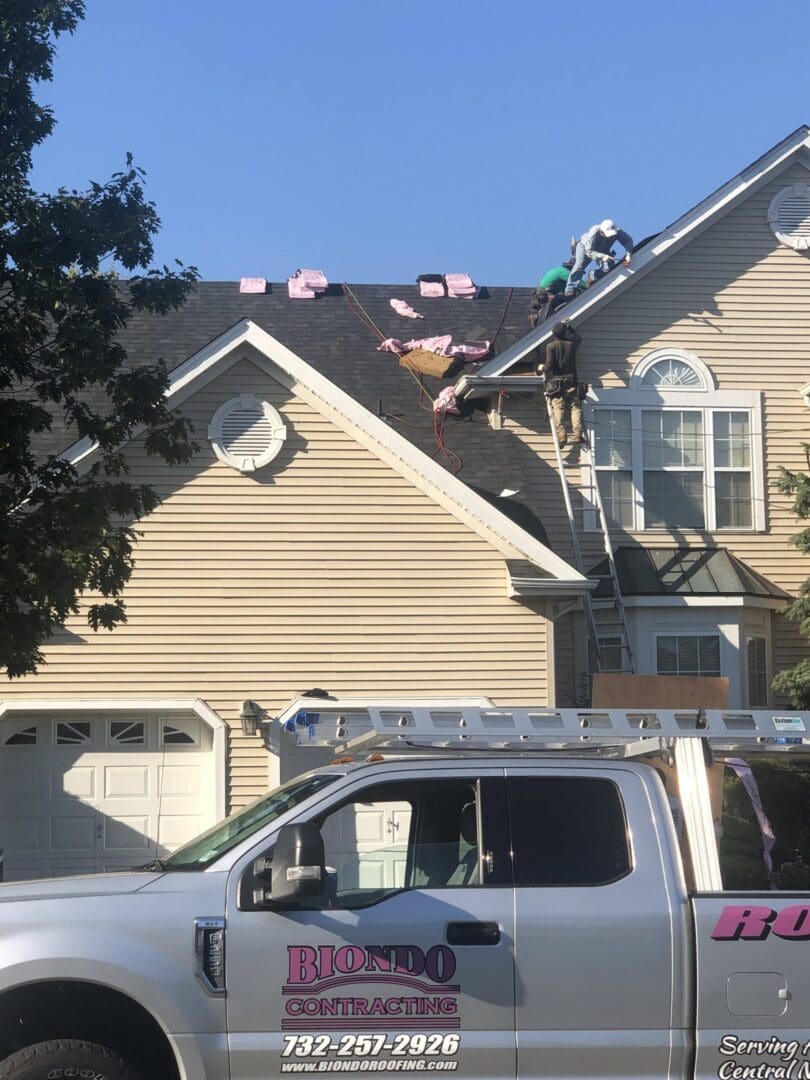 A truck parked in front of a house with a roof being installed.