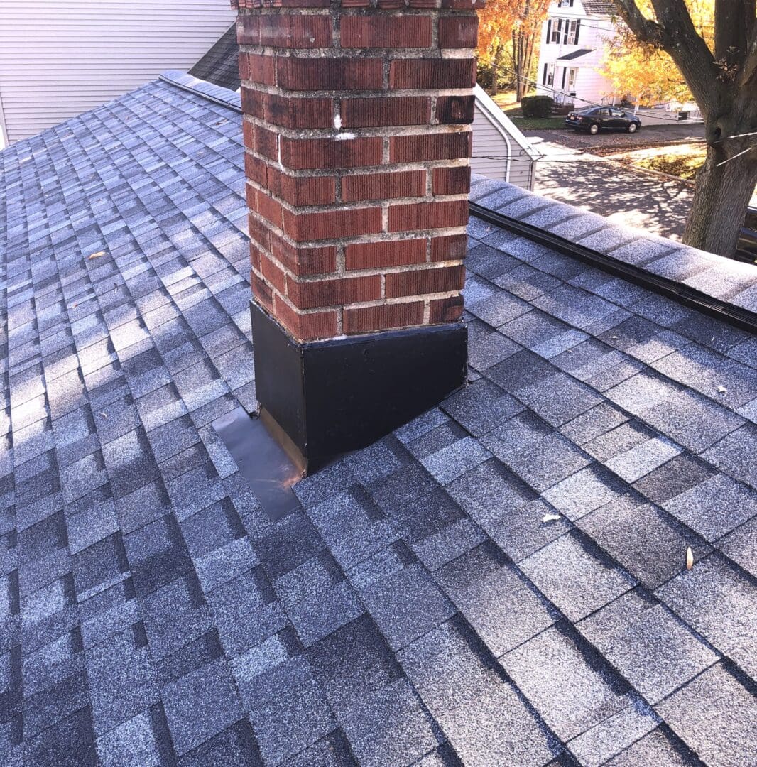 A brick chimney with new black flashing on the top of a roof.