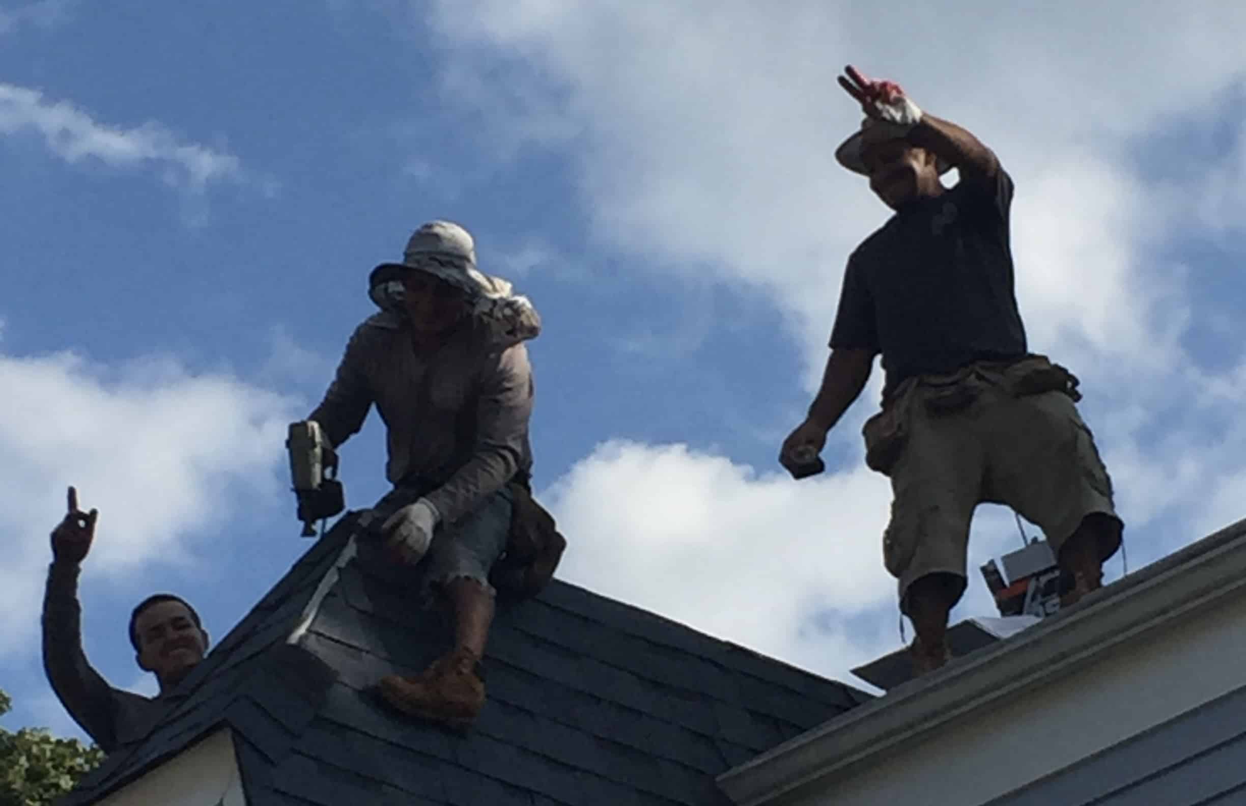 Two men standing on top of a roof.