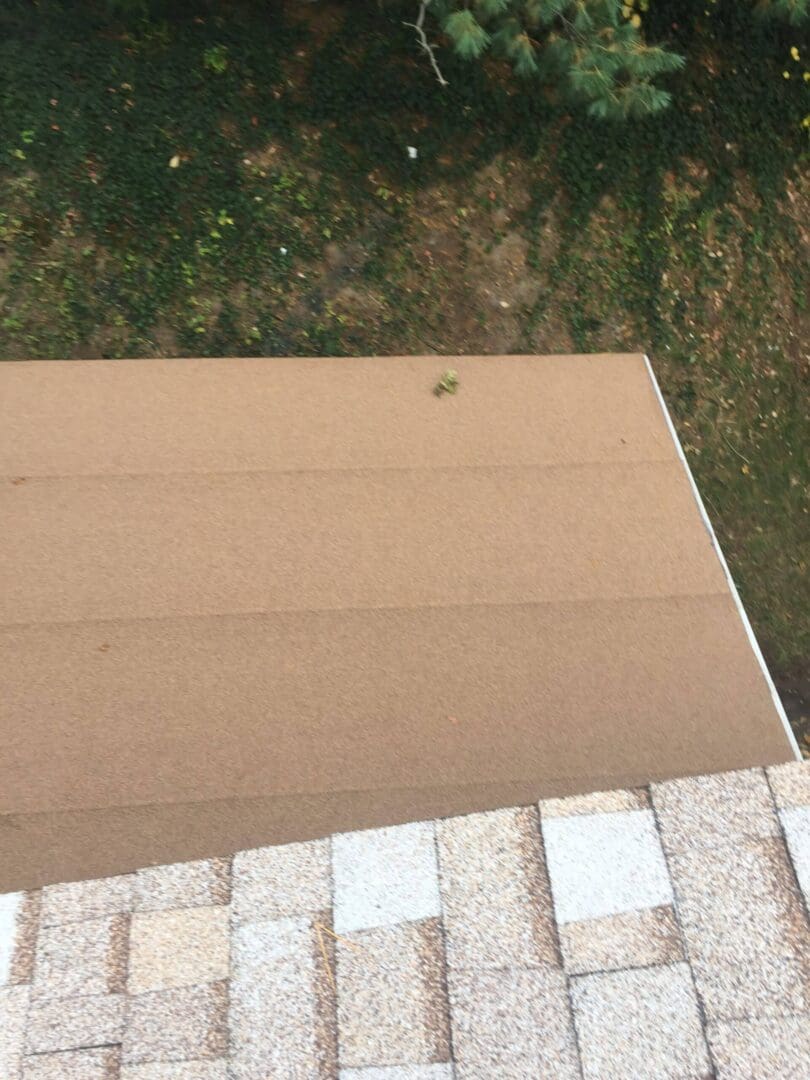 A Tan colored flat roof next to a shingled roof.