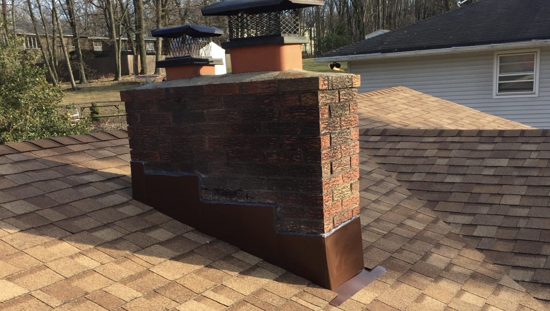 A brick chimney with new brown flashing.