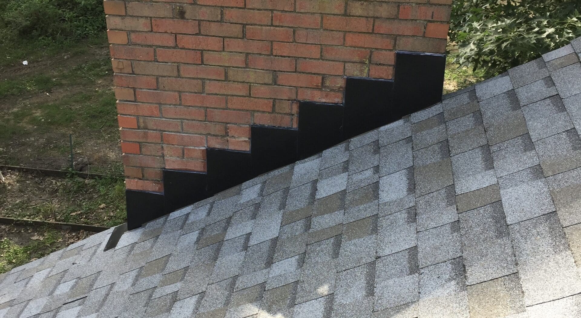 a brick chimney with black colored stepped counter flashing