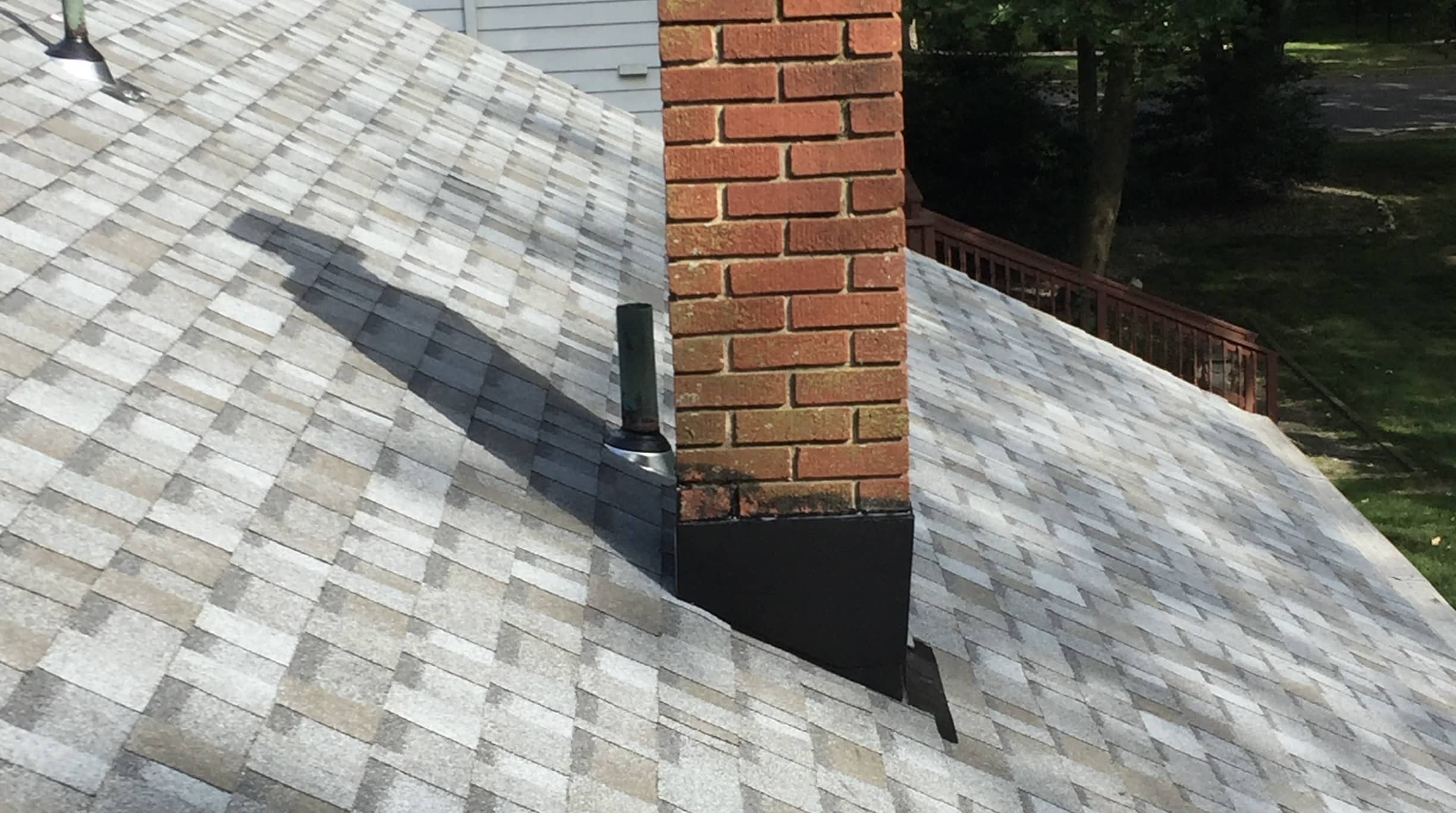 A brick chimney with new black colored flashing.