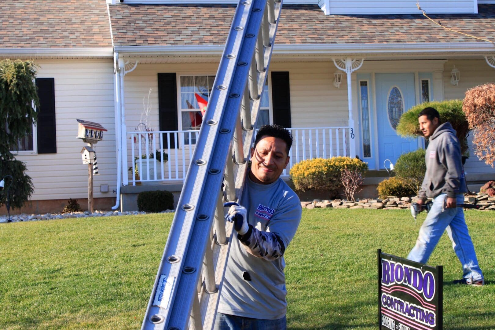 A man standing next to a ladder in front of a house.