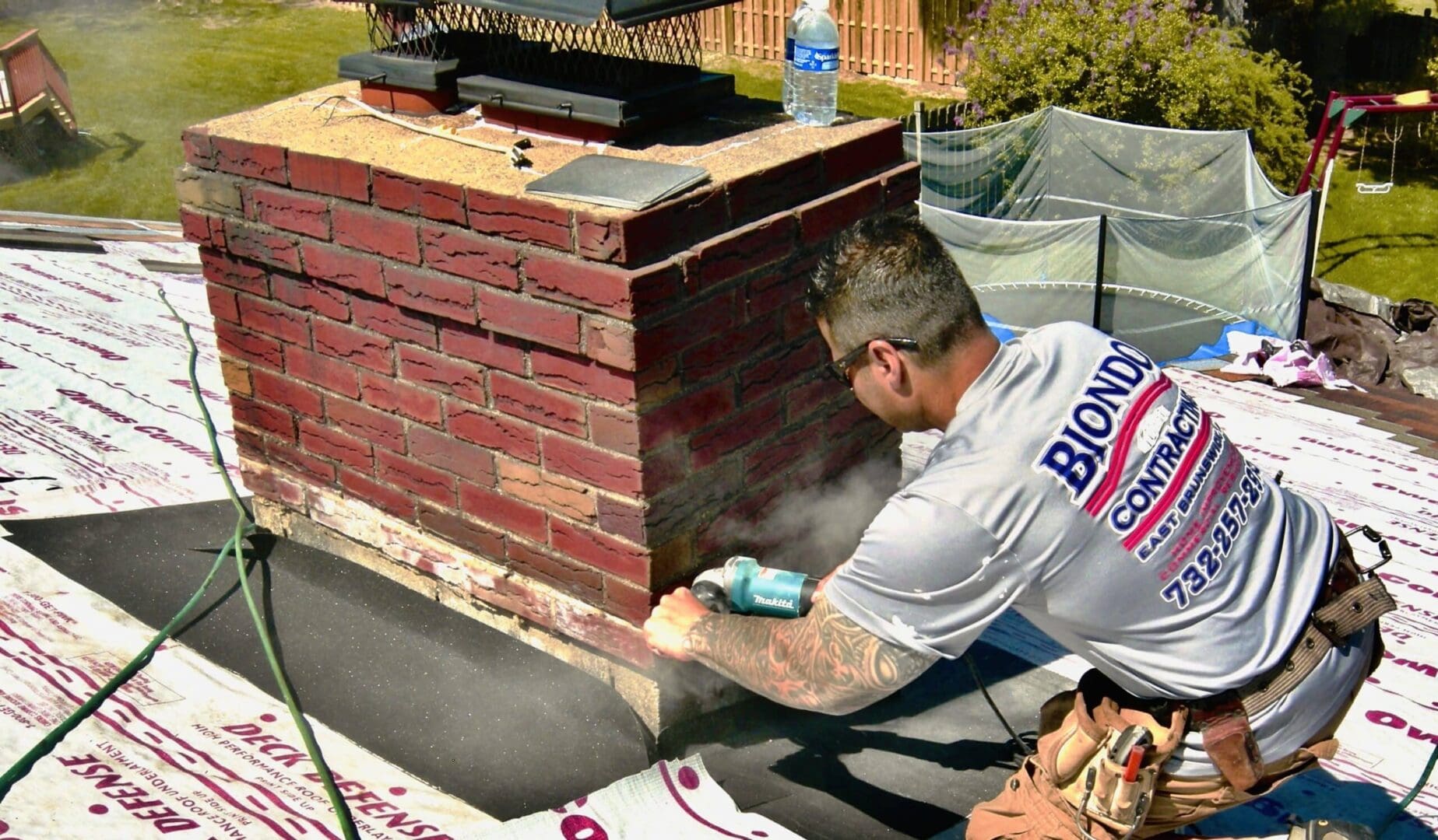 A man is painting the brick of a fireplace.