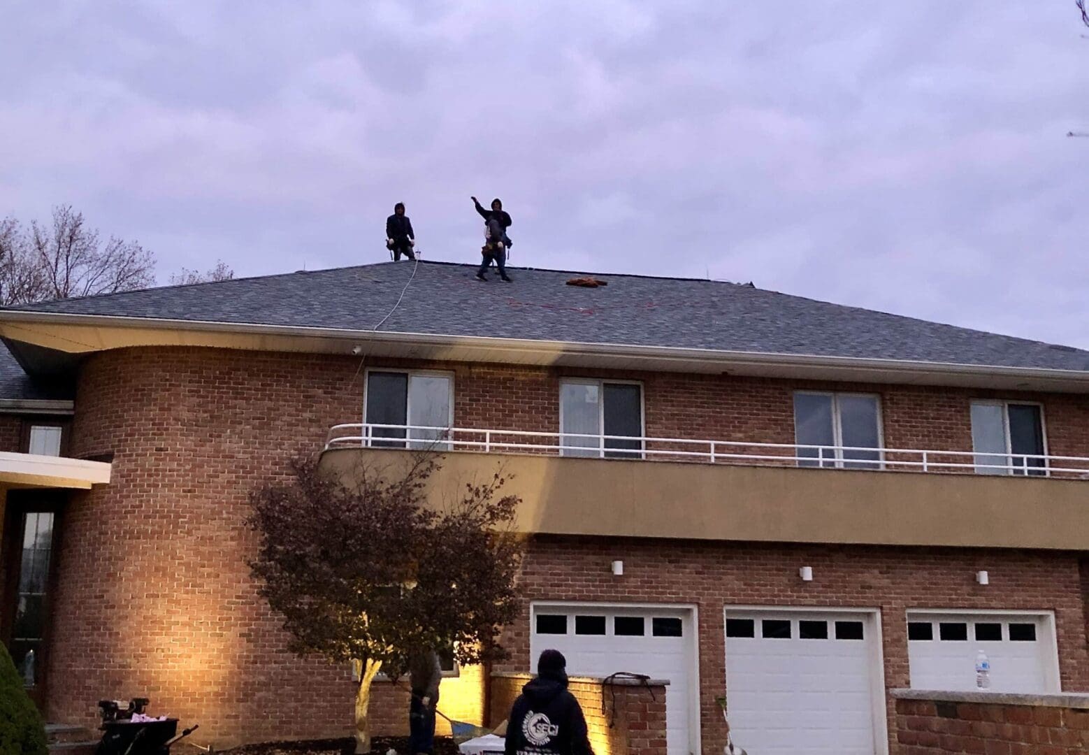 Two men standing on the roof of a house.