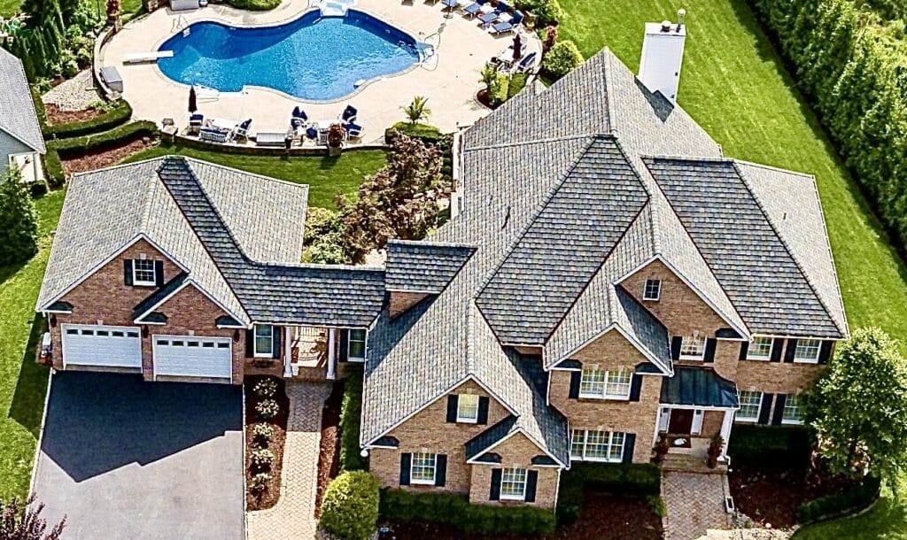 A large brick house with a gorgeous roof and pool in the background. Monroe NJ Roof Repair