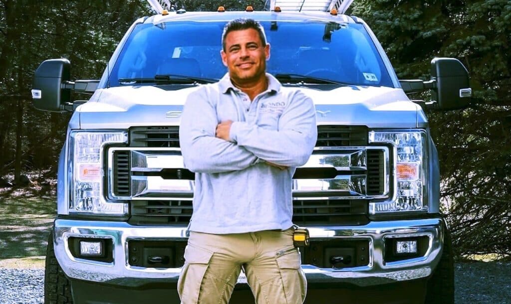 Roofing Contractor employee standing in front of truck