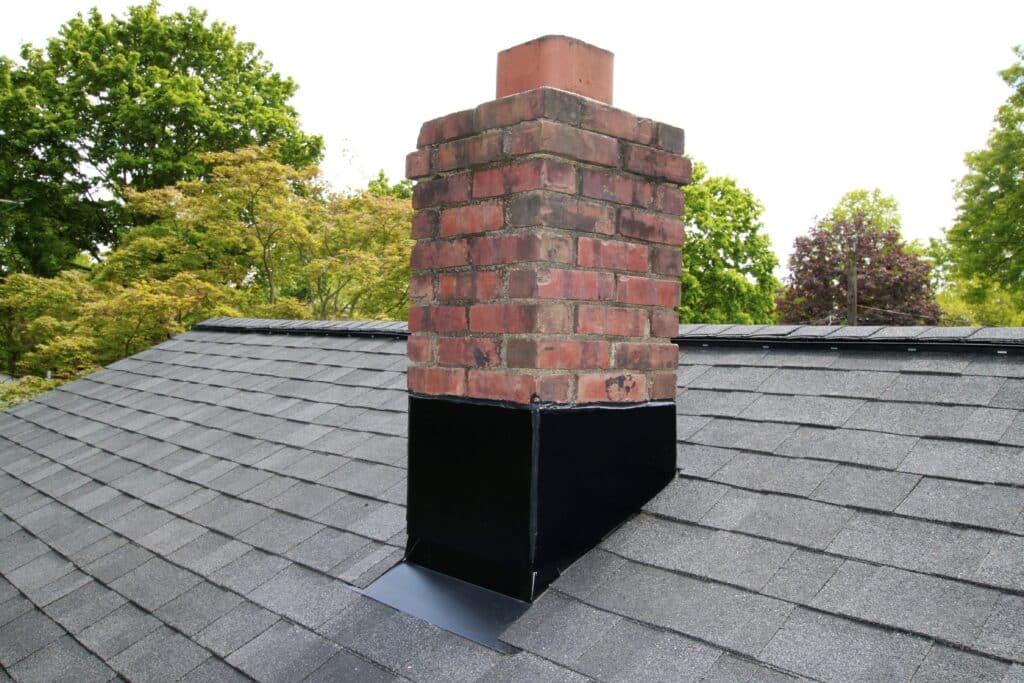 Old Bridge Roofers Red Brick chimney on a black roof with new black flashing.