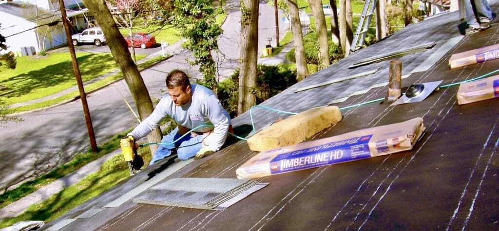 Boss of roofing company on roof nailing roofing shingles